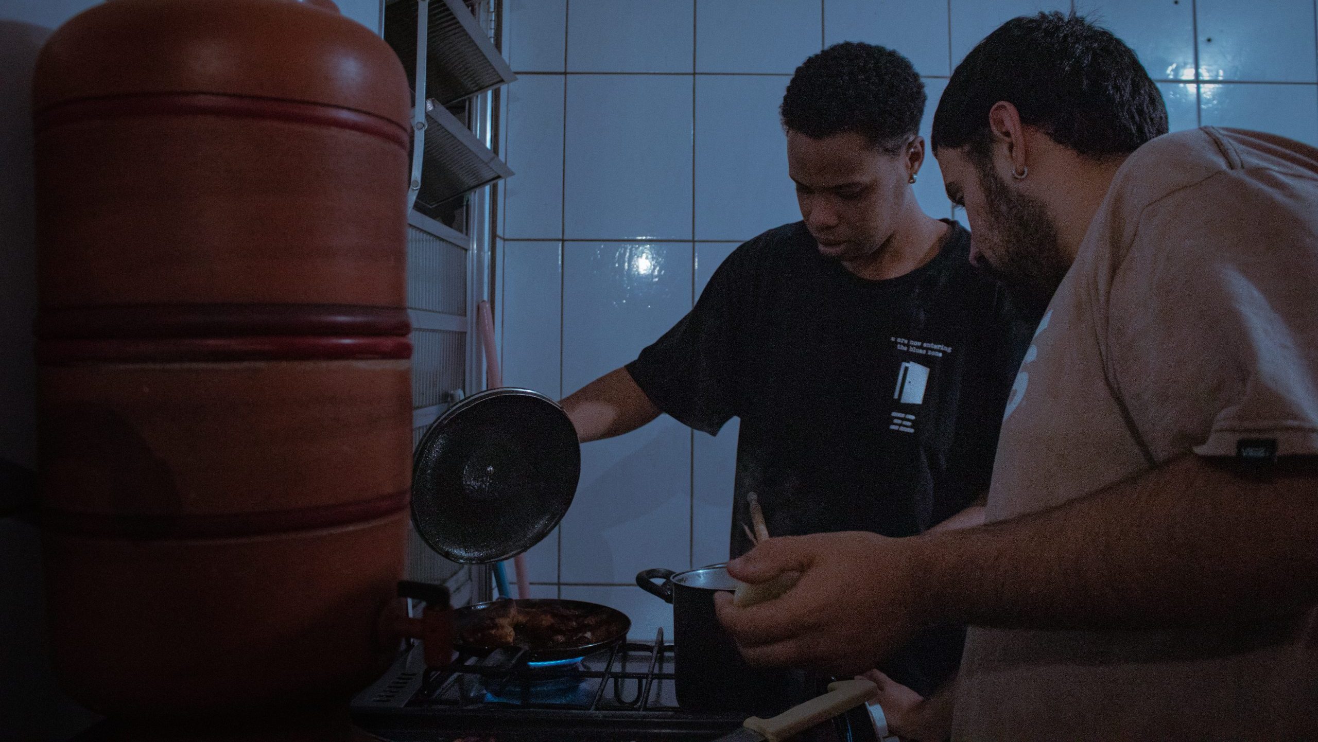 Bruno Sena (ele/dele), à esquerda; e Aquilla Xavier (ele/dele), à direita, cozinhando juntos