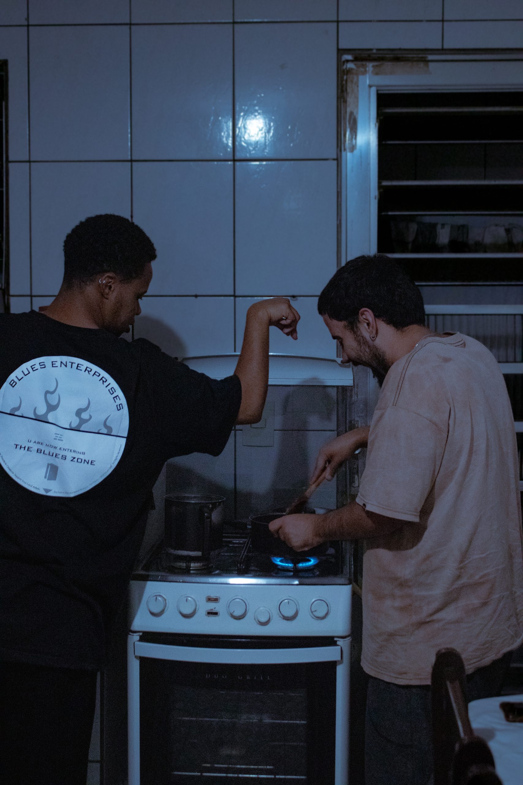 Bruno Sena (ele/dele), à esquerda; e Aquilla Xavier (ele/dele), à direita, cozinhando juntos.