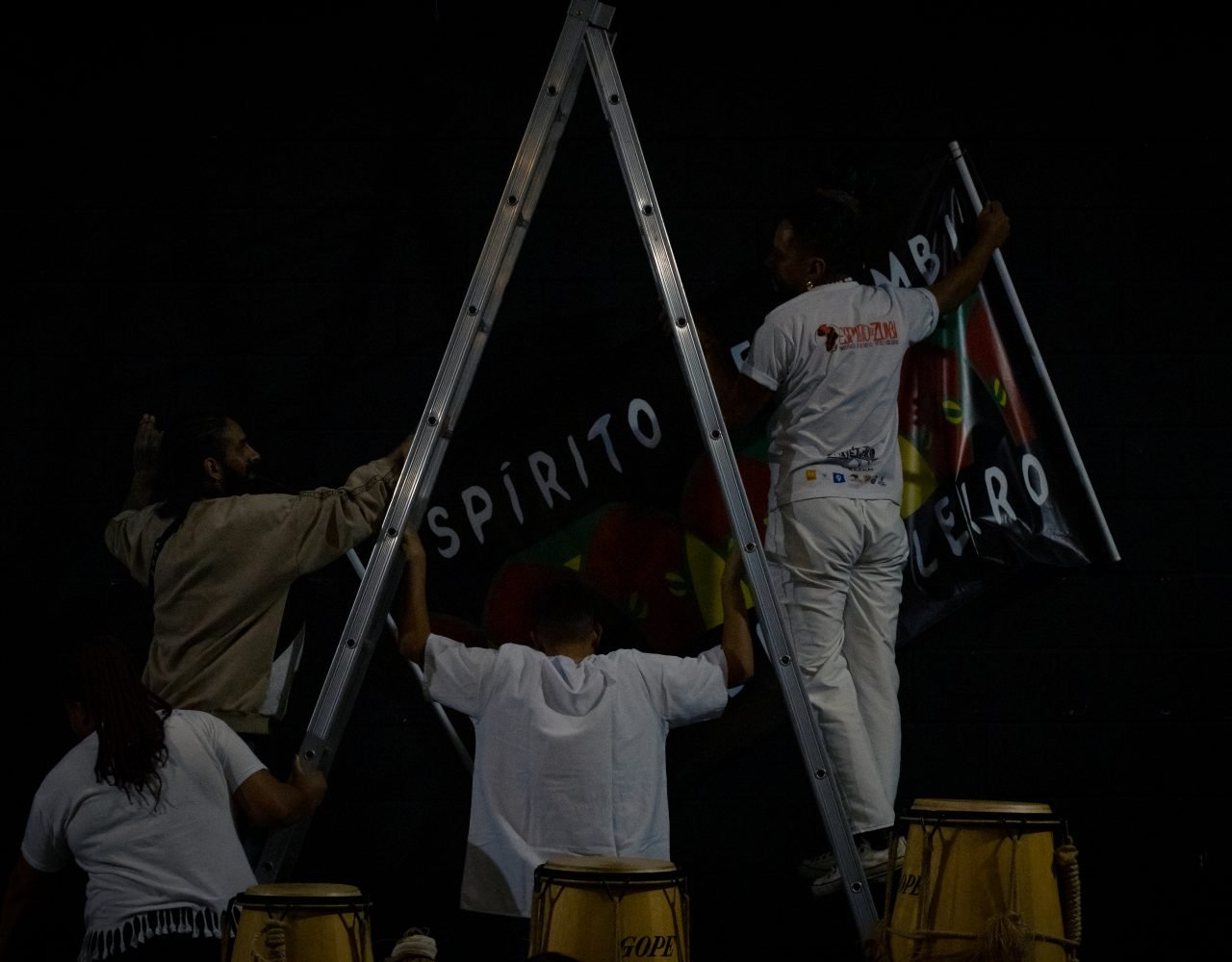 Integrantes do Espirito de Zumbi, penduram faixa com nome do grupo no galpão - PANELAFRO_evento_culturapopular_zona sul_vitorijumapili-34