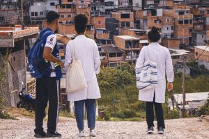 Agente de saúde falando sobre o bairro para as médicas.