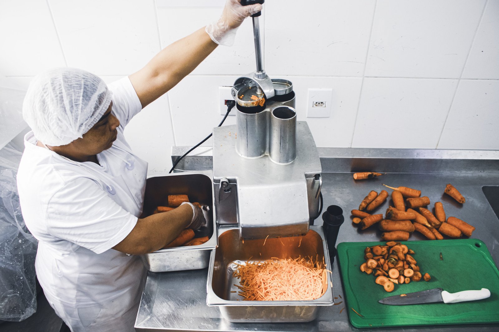Maria Cristina Vieira dos Santos, auxiliar de cozinha, ralando cenoura