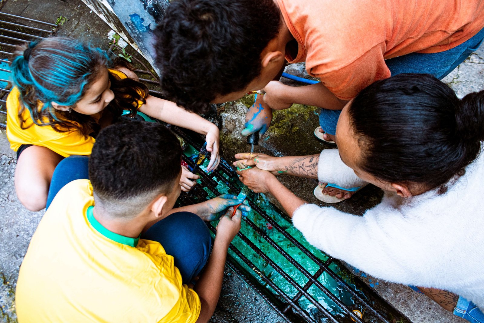 Participantes da mobilização de pintura da rua no Jardim Ibirapuera lavam as mãos e os pincéis manchados de tinta