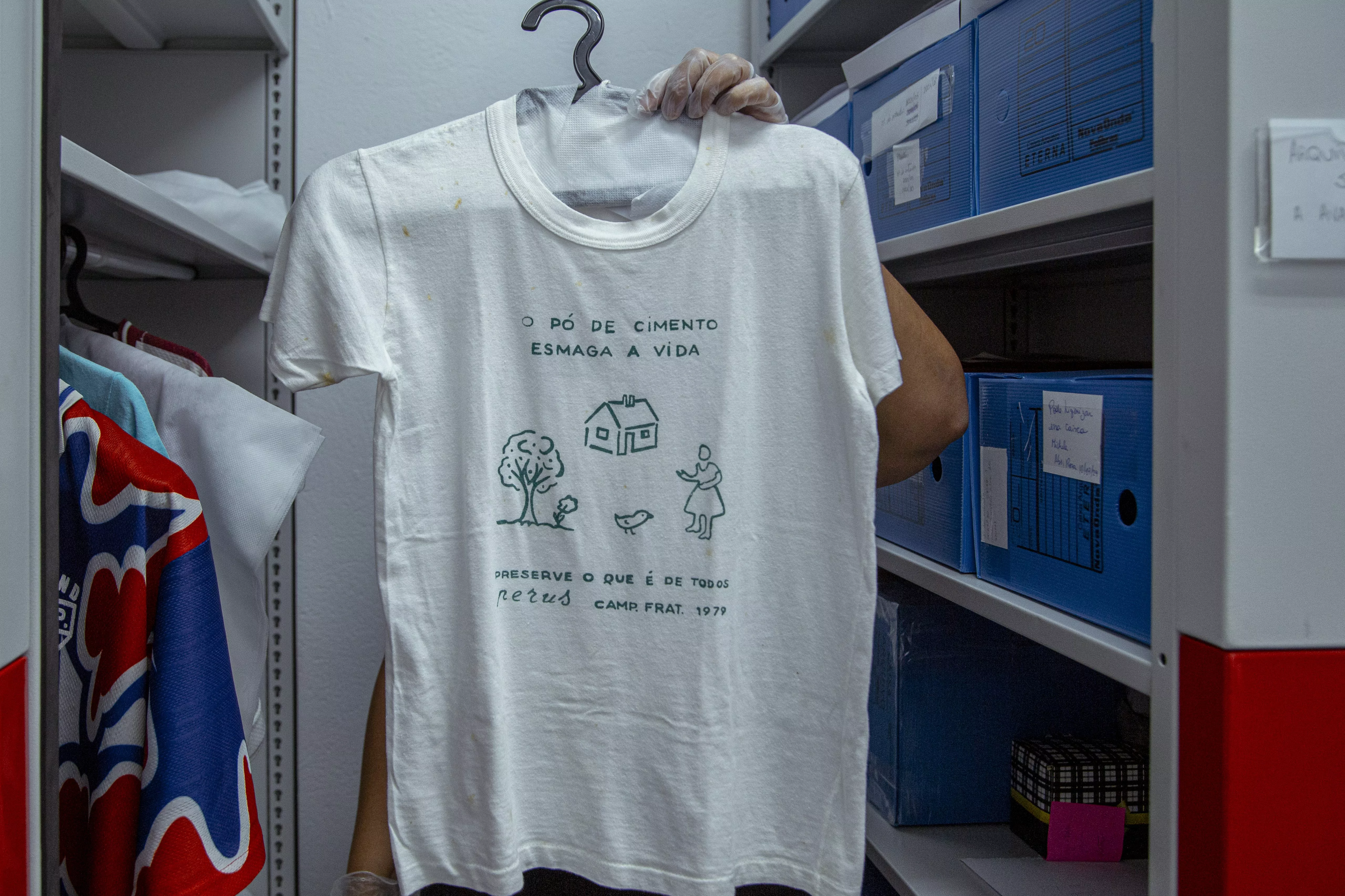 Sheila Moreira manuseia coleção de camisas do acervo. Dentre elas, do clube de mães do bairro e do time da região na época da fábrica